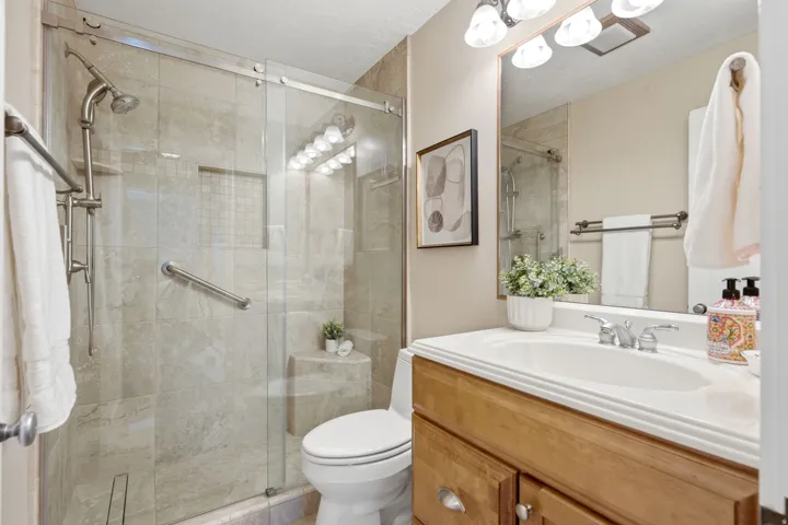 Enclosed shower with full-height tile surround, built-in bench, and sliding glass door