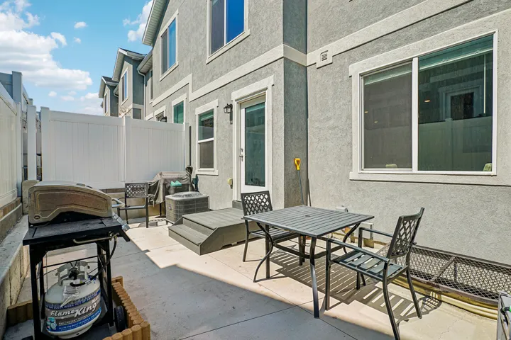 Private outdoor patio with a concrete surface, white vinyl fencing, and a built-in deck platform