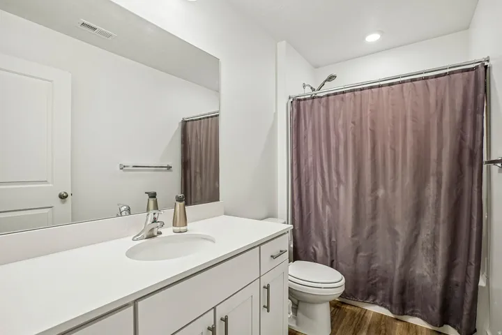 Bathroom featuring a white vanity with an integrated sink, brushed nickel faucet, and a large wall-mounted mirror