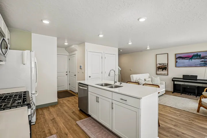 Modern kitchen featuring a central island with an undermount sink, white cabinetry, and light-toned countertops