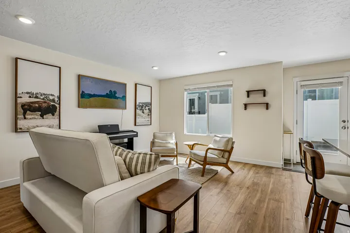 Open-concept living area featuring wood-finish flooring, recessed lighting, a modern window, and a glass-paneled door