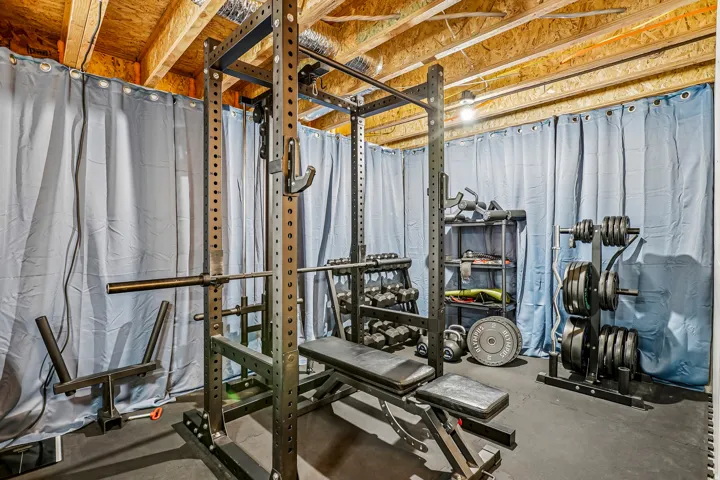 Dedicated fitness studio featuring industrial steel framework with multiple workout stations, rubber flooring, and comprehensive weight storage systems