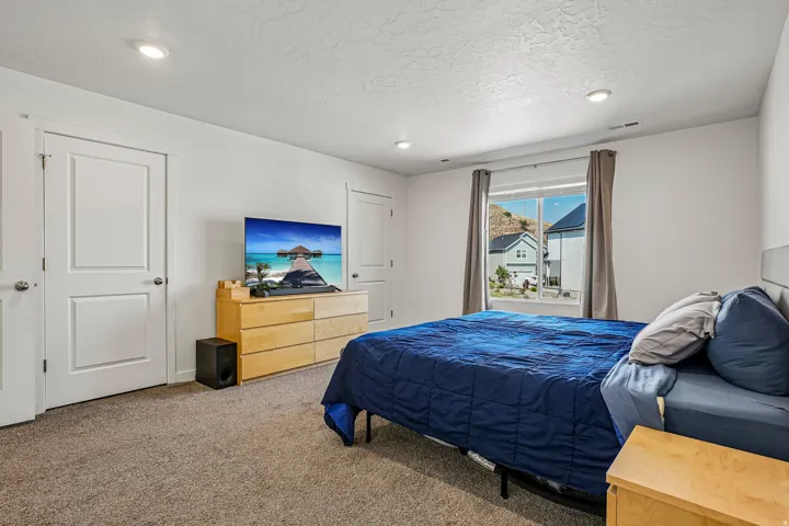 Carpeted bedroom featuring recessed lighting and a large window with mountain scenery