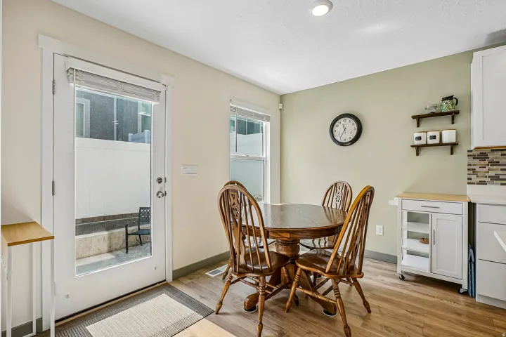 Dining area featuring wood-finish flooring, a full-lite door with integrated blinds, and light green accent walls