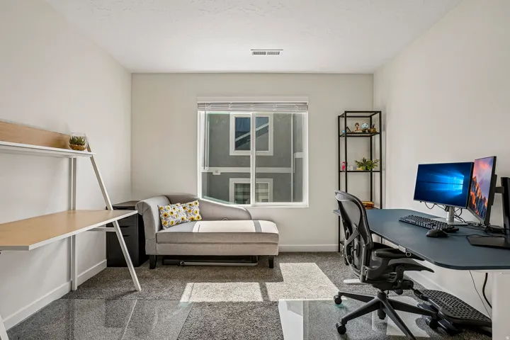 Bright room with large window, light-toned walls, and grey patterned carpeting