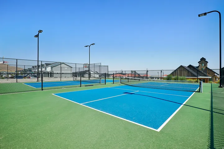 Multiple outdoor sports courts featuring a vibrant blue playing surface and green surrounds