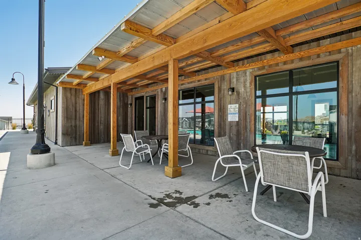 Modern rooftop terrace featuring a wooden pergola structure with integrated shade panels, concrete decking, and floor-to-ceiling glass doors providing seamless access to interior spaces