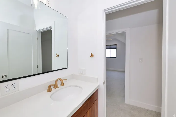 Bathroom vanity featuring a single undermount sink, a wide countertop, and warm-toned wood cabinetry