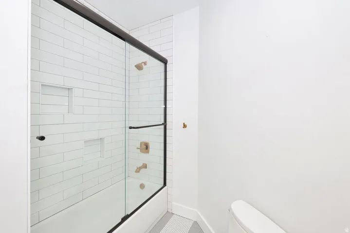 Bathtub-shower combination featuring a frameless glass enclosure with matte black trim