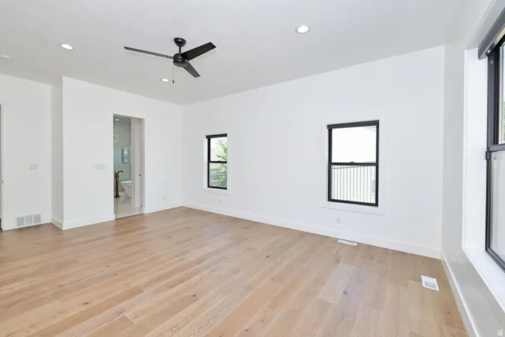 Spacious room featuring light wood-finish flooring, recessed lighting, and a modern ceiling fan