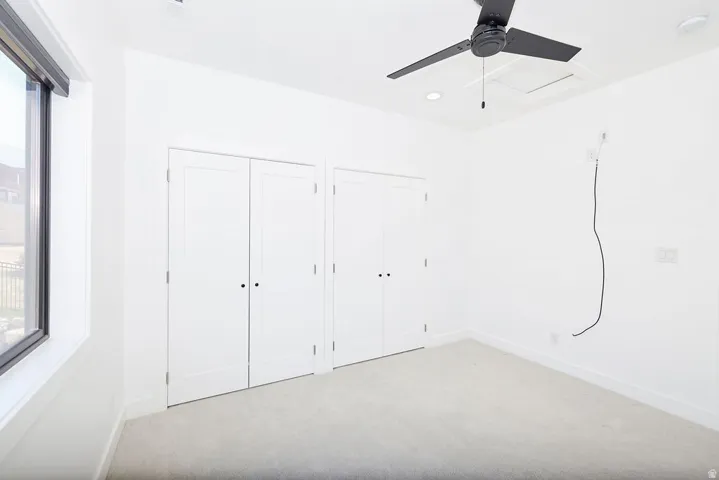 Room featuring light gray carpeting, crisp white walls, and a large window with black trim