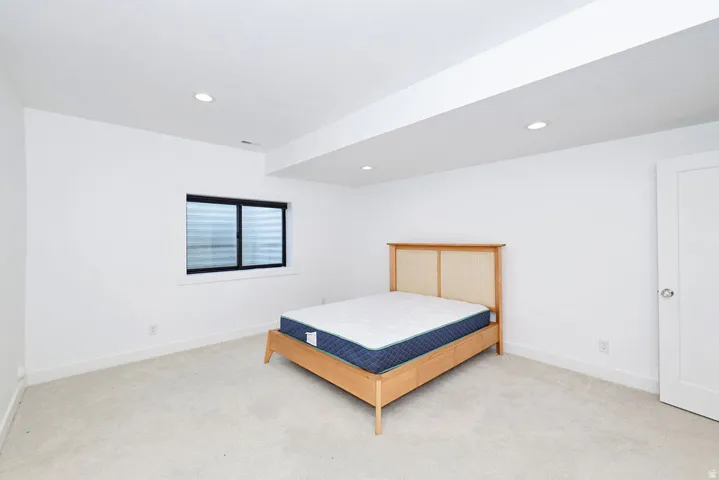 Carpeted room featuring recessed lighting, a white painted door, and a single window with horizontal blinds