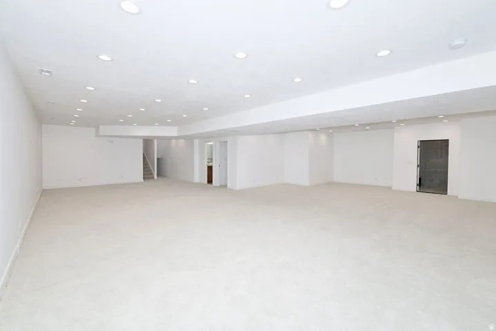 Spacious room featuring light-toned carpeting, recessed ceiling lighting, and white wall finishes