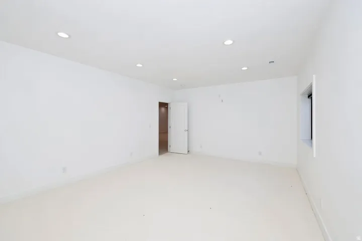 Spacious room featuring neutral carpeting and recessed lighting