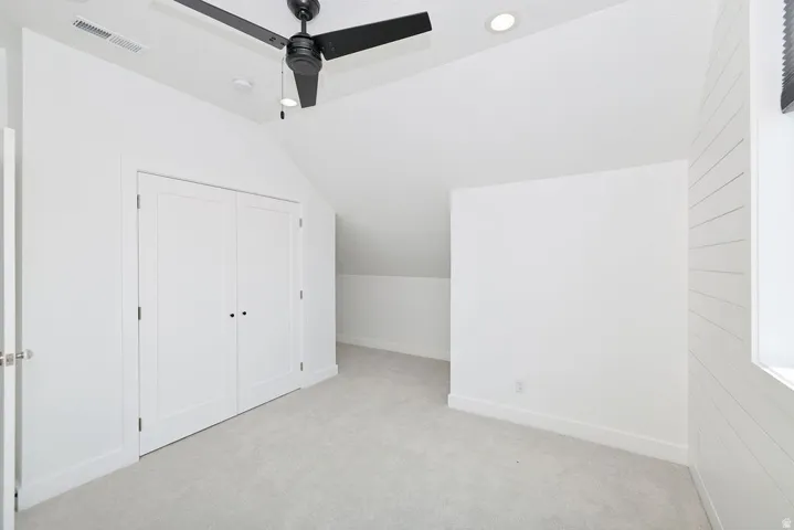 Carpeted room with a black ceiling fan, recessed lighting, and white bi-fold closet doors
