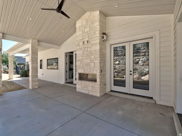 Covered patio featuring a stone-clad fireplace and dual glass-paned doors