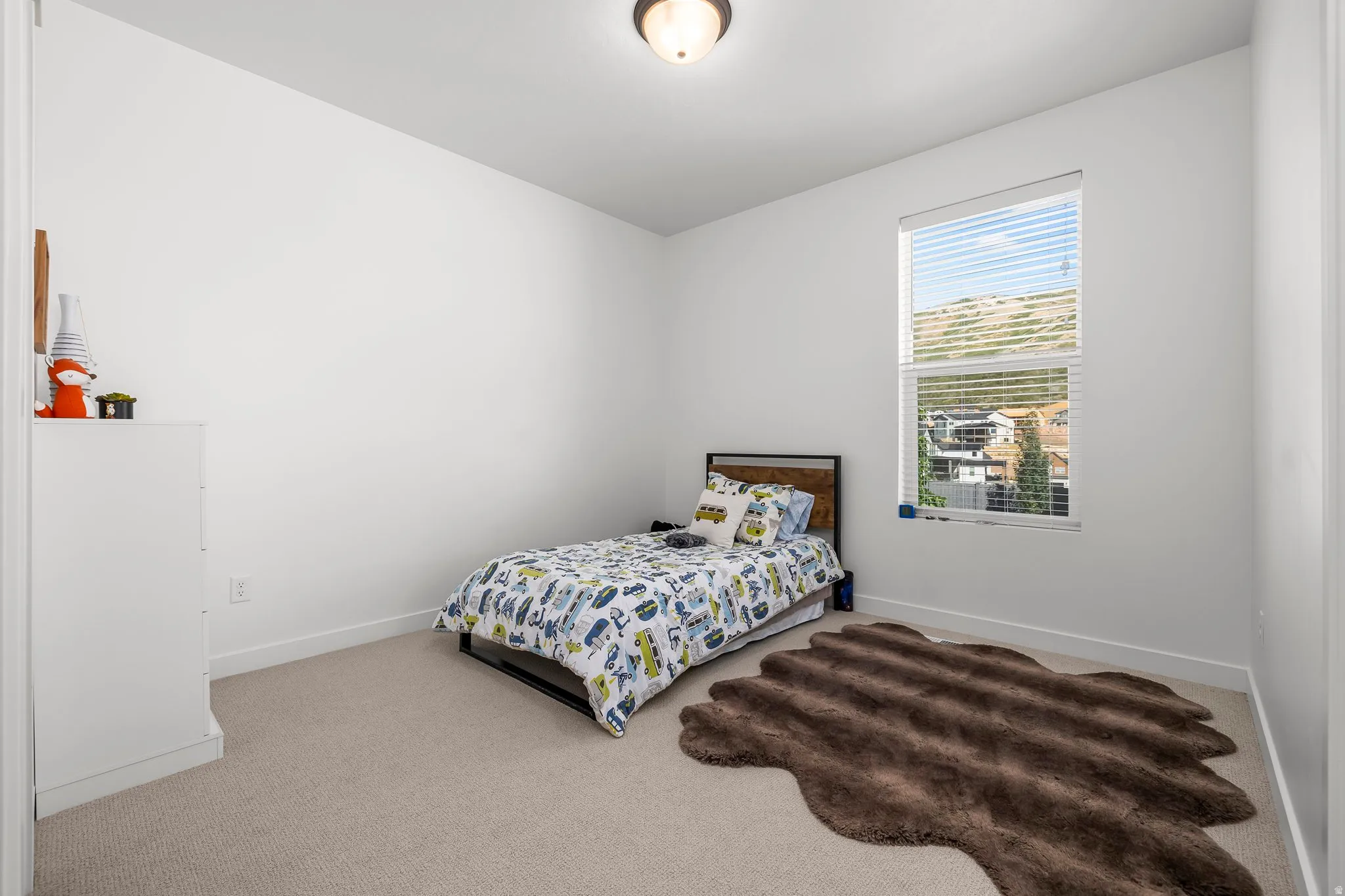 Carpeted room with a large window featuring horizontal blinds