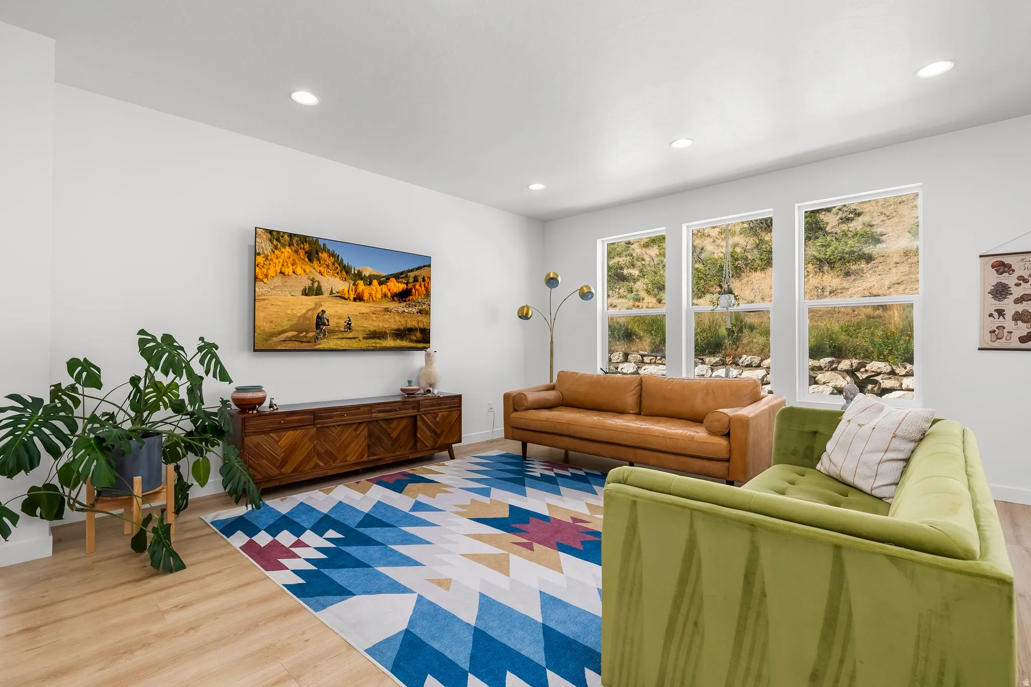 Spacious living area featuring light wood-finish flooring, recessed lighting, and bright white walls