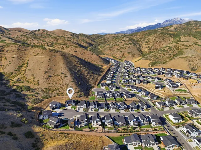 Aerial perspective showcasing a developed residential community with modern homes against a backdrop of natural mountainous terrain