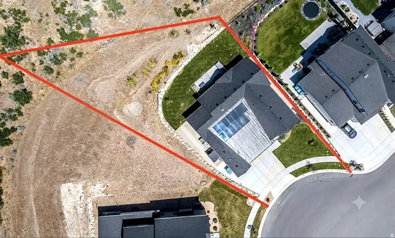 Aerial view showcasing expansive grounds with manicured lawn, mature landscaping, and modern residential structures featuring dark roofing and solar panel installation