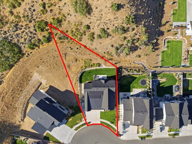 Aerial view of a property featuring a multi-level home with a dark roof and solar panels