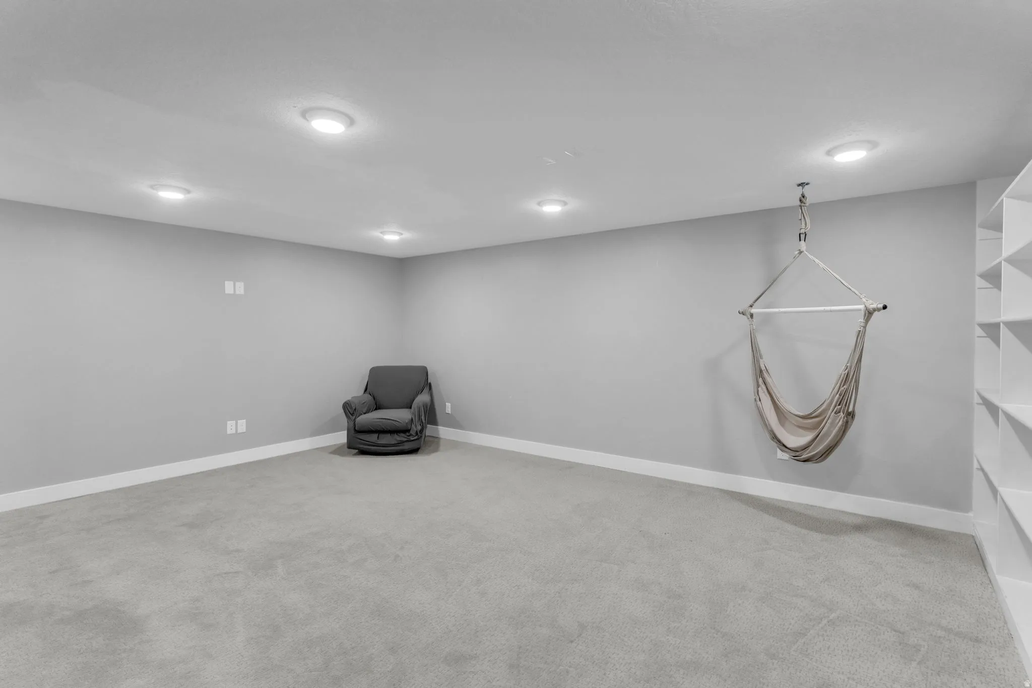 Spacious room featuring light gray carpeting, recessed lighting, and a white baseboard trim