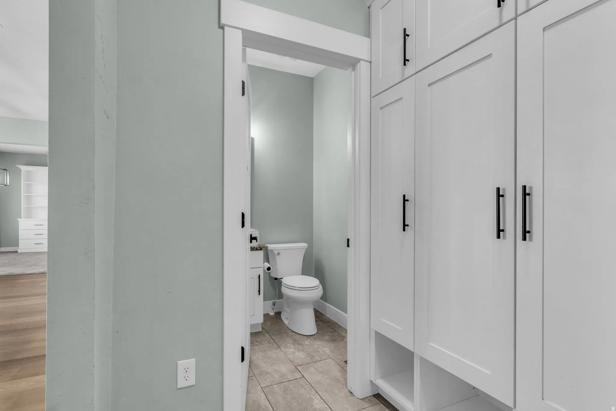 Powder room featuring a pedestal toilet, white vanity with a rectangular sink, and a wall-mounted mirror