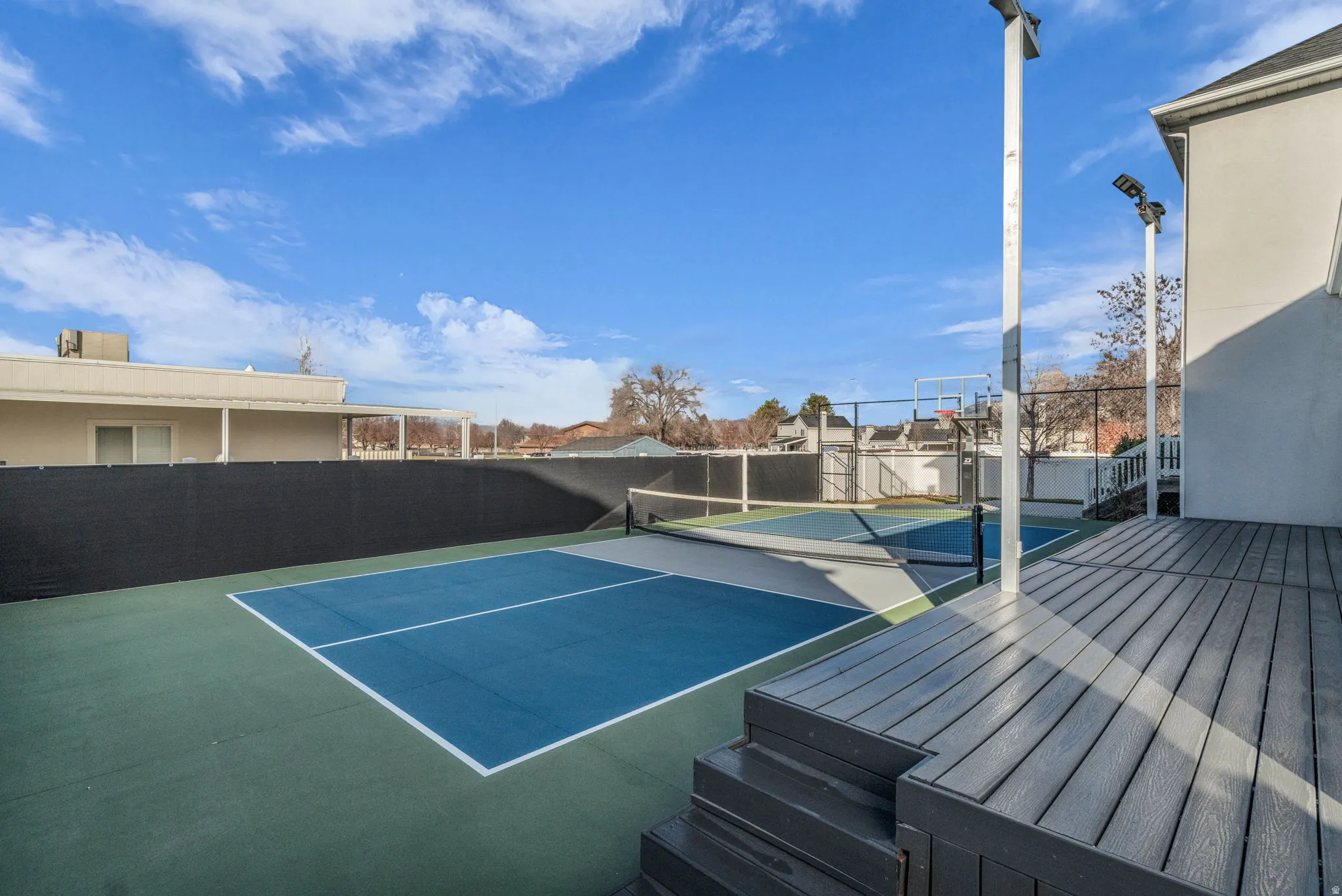 Multi-sport court featuring a pickleball setup and basketball hoop