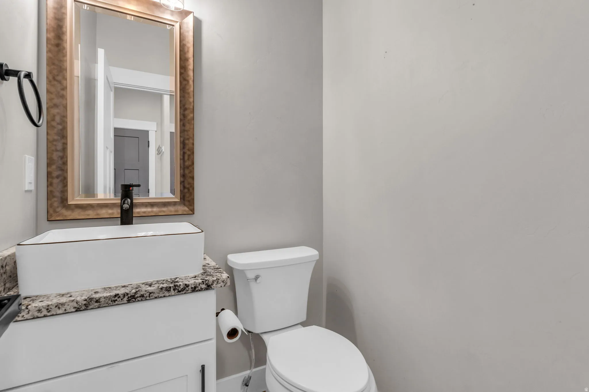 Modern bathroom vanity featuring a rectangular vessel sink, dark-toned faucet, and a light granite-finish countertop