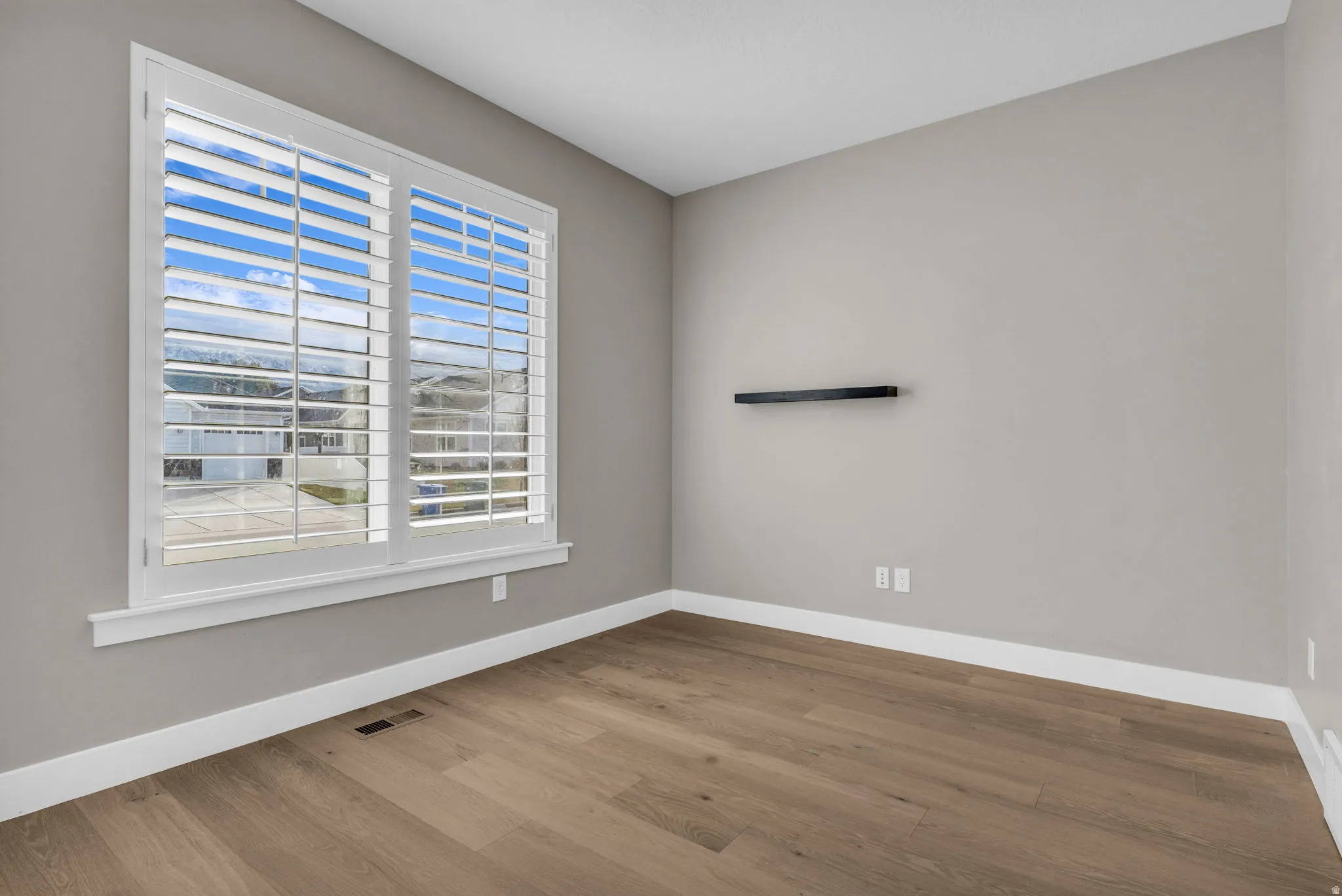 Room featuring wood-finish flooring, neutral wall tones, and white baseboards