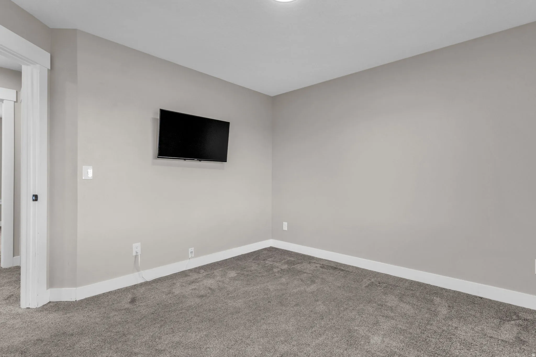 Room with neutral-toned walls, plush gray carpeting, and white baseboards