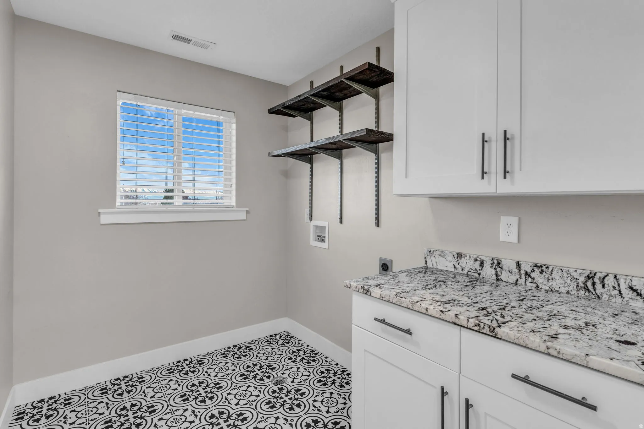 Laundry area featuring white cabinetry, a light-toned countertop, and patterned flooring
