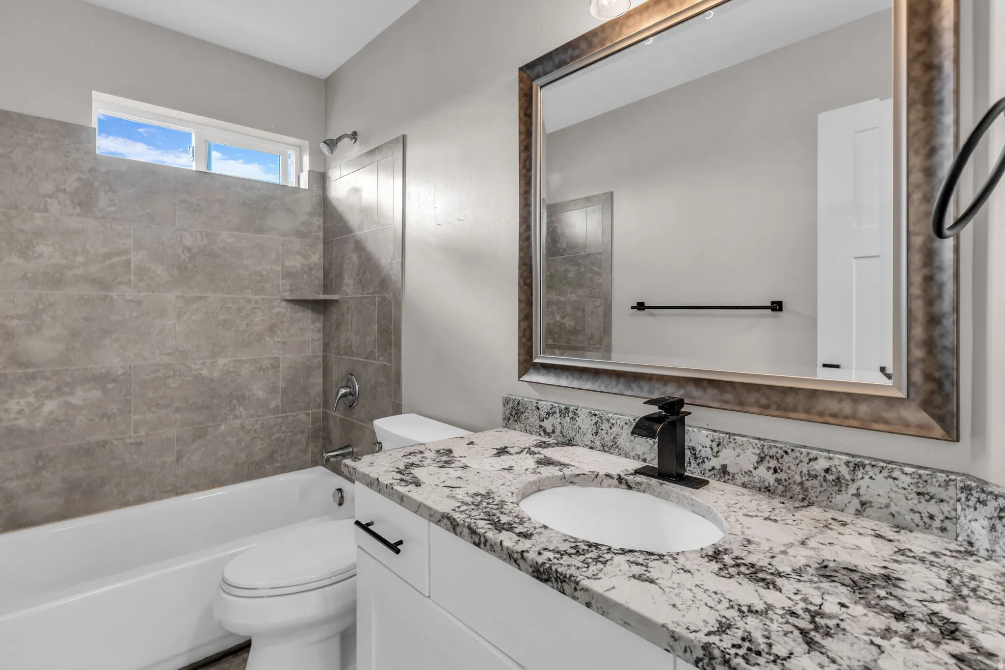 Bathroom vanity with a waterfall faucet, an under-mount sink, and a speckled countertop