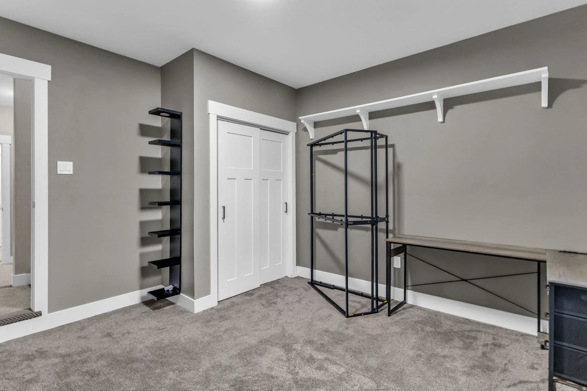 Carpeted room featuring a white trim package, gray wall color, and a built-in shelving unit