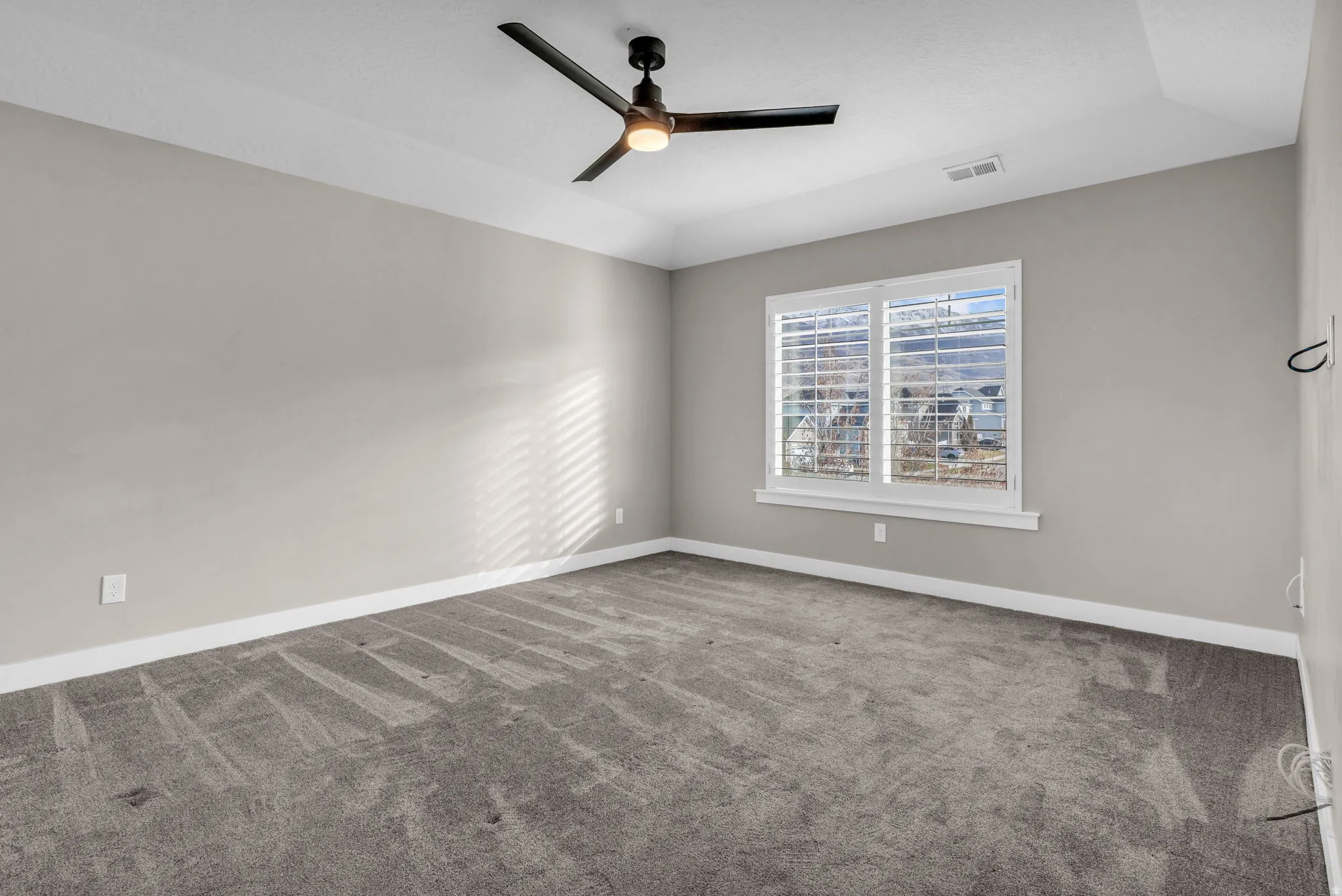 Carpeted room with a ceiling fan, recessed lighting, and a window featuring white plantation shutters