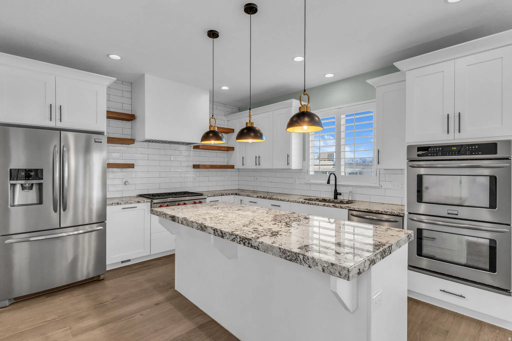 Gourmet kitchen featuring white shaker cabinetry, stainless steel French-door refrigerator, dual wall-mounted ovens, and a gas cooktop
