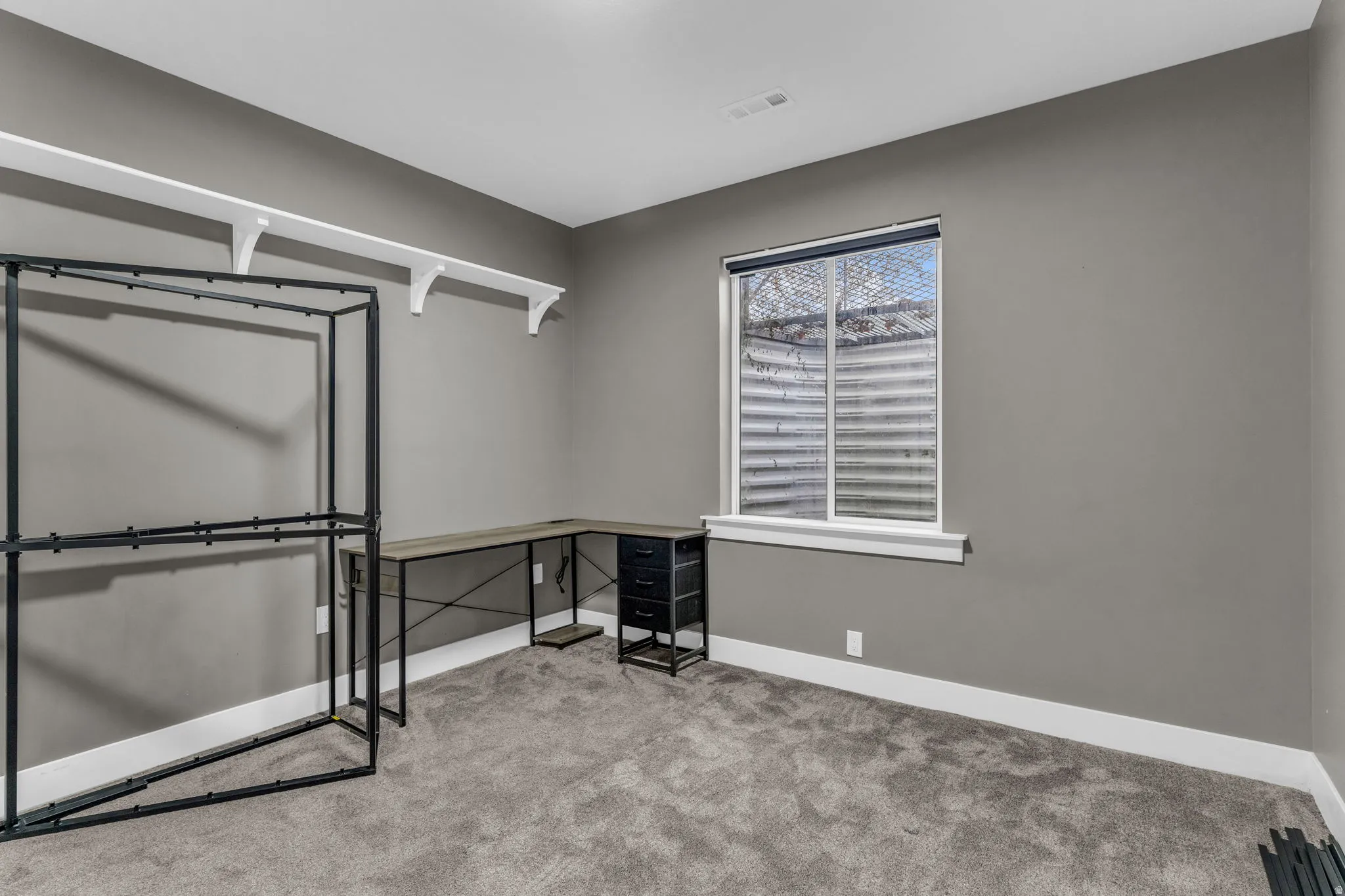 Carpeted room featuring a single window with white trim, gray wall paint, and white baseboards