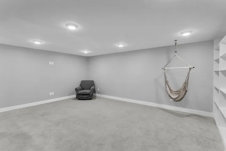 Spacious room featuring light gray carpeting, recessed lighting, and a white baseboard trim