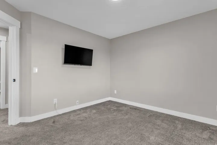 Room with neutral-toned walls, plush gray carpeting, and white baseboards