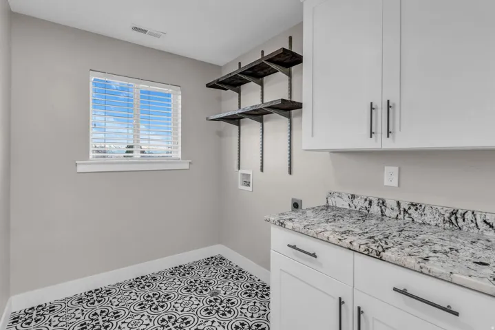 Laundry area featuring white cabinetry, a light-toned countertop, and patterned flooring