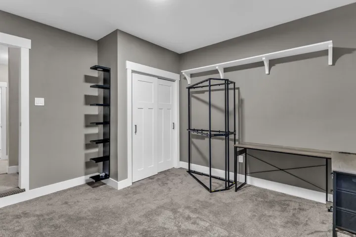 Carpeted room featuring a white trim package, gray wall color, and a built-in shelving unit