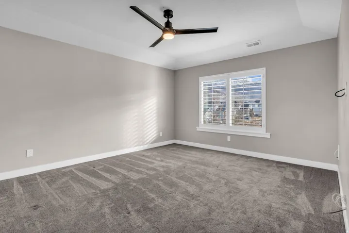 Carpeted room with a ceiling fan, recessed lighting, and a window featuring white plantation shutters