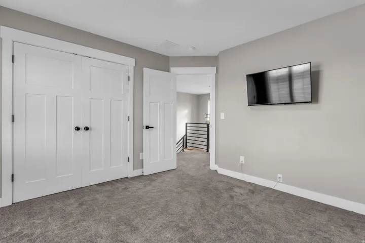 Gray-toned carpeted room featuring white paneled doors with black hardware, neutral wall paint, and white trim