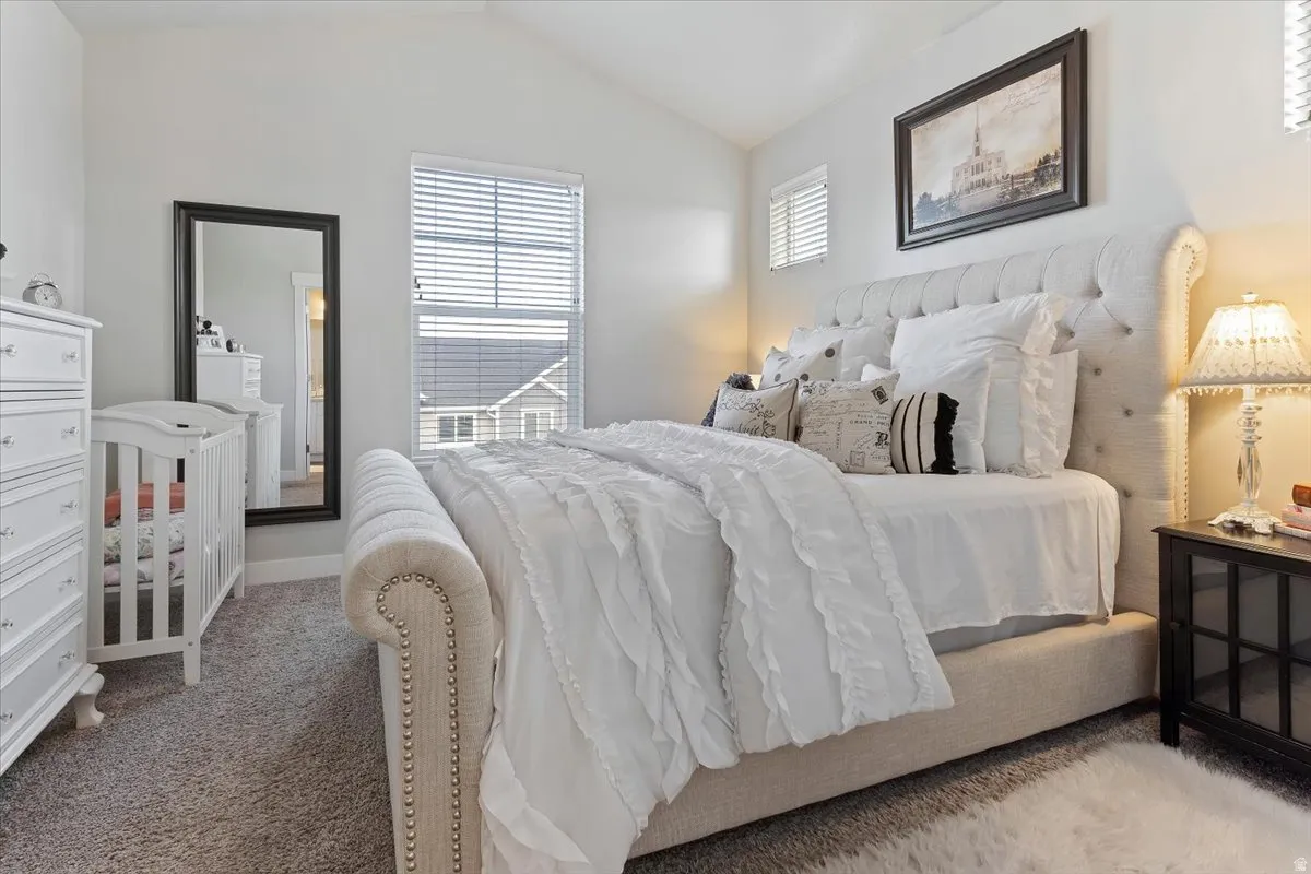 PRIMARY SUITE - Vaulted ceilings enhancing the room's height, plush carpeting providing comfort, and multiple windows allowing natural illumination