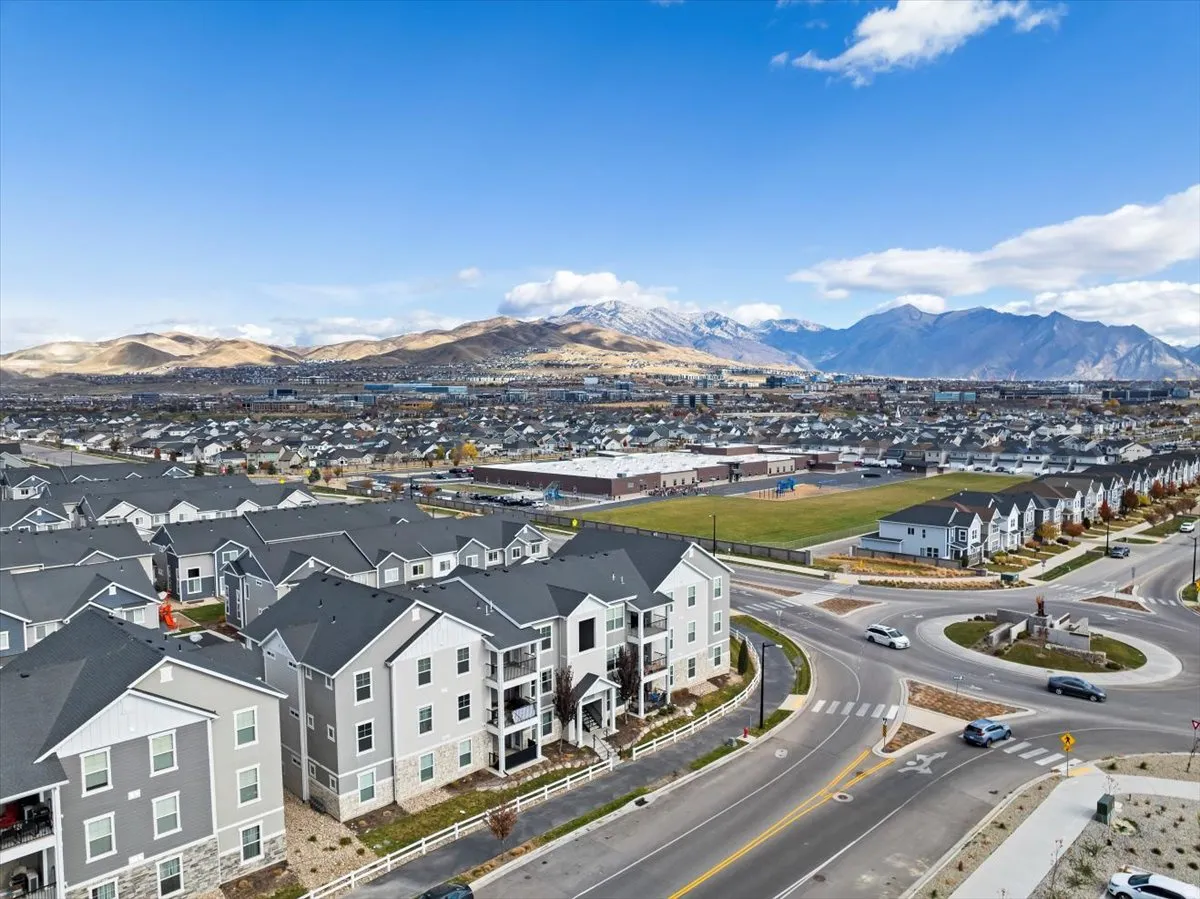 NEIGHBORHOOD - Expansive neighborhood aerial featuring multiple residential buildings, a central roundabout, and distant mountains