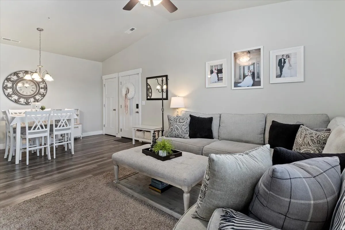 Open-concept living space featuring vaulted ceilings, wood-finish flooring, a contemporary ceiling fan, and a dining area with pendant lighting