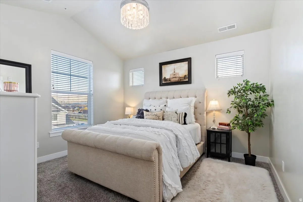 PRIMARY SUITE - Vaulted ceiling with a chandelier, grey wall paint, and plush grey carpeting