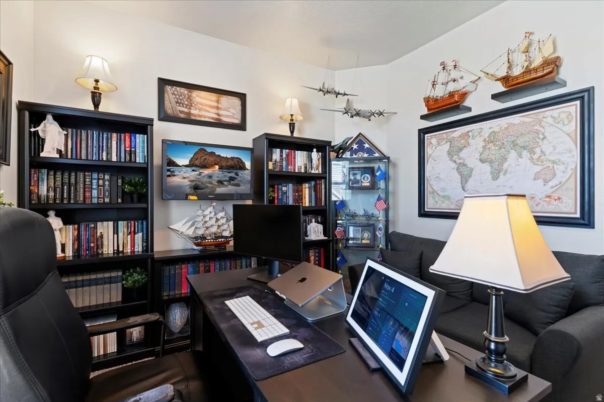 Dedicated office space featuring built-in bookshelves, a wall-mounted television, and a spacious desk area