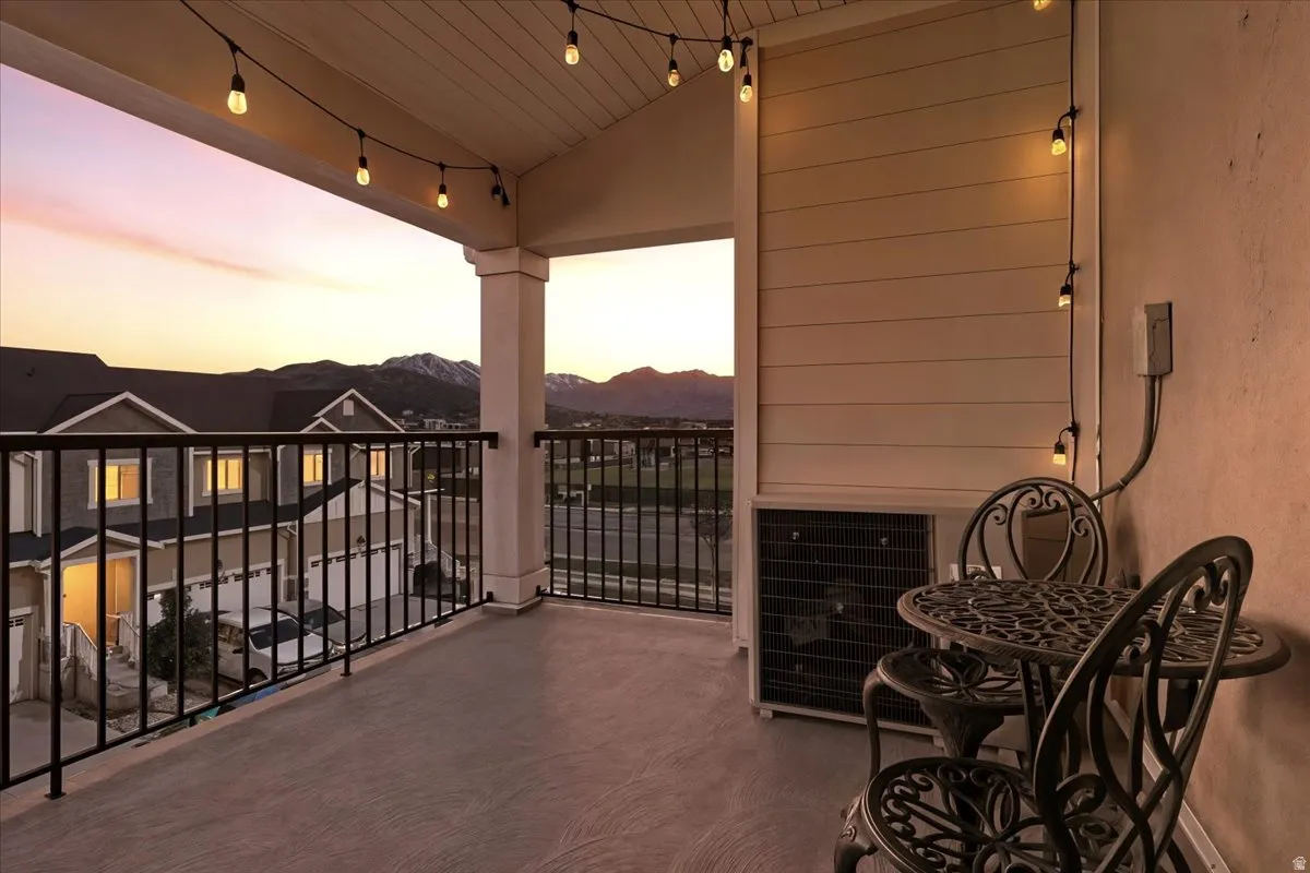 Covered balcony with composite flooring, metal railings, string pendant lighting and gorgeous views