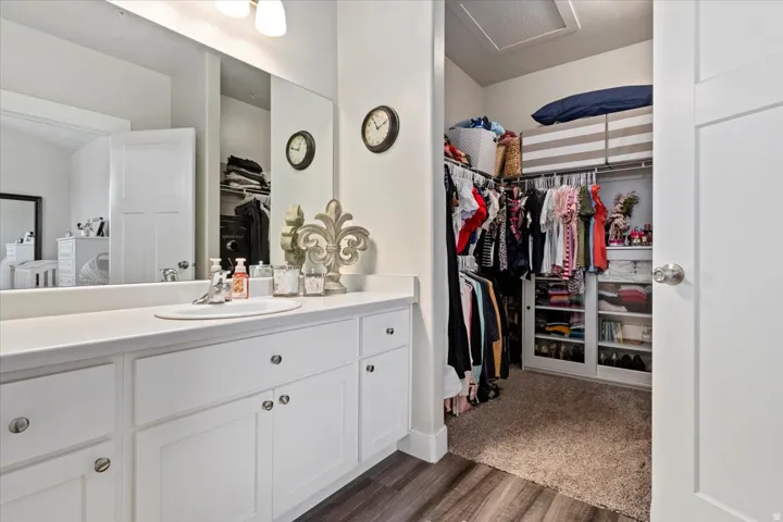 PRIMARY BATH & WALK-IN CLOSET - Bathroom vanity with a white countertop and integrated sink, complete with white cabinetry and chrome hardware
